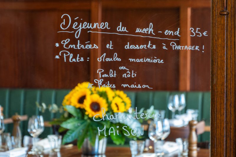 L'ardoise du déjeuner du week-end, écrite sur le grand miroir derrière un bouquet de tournesols.