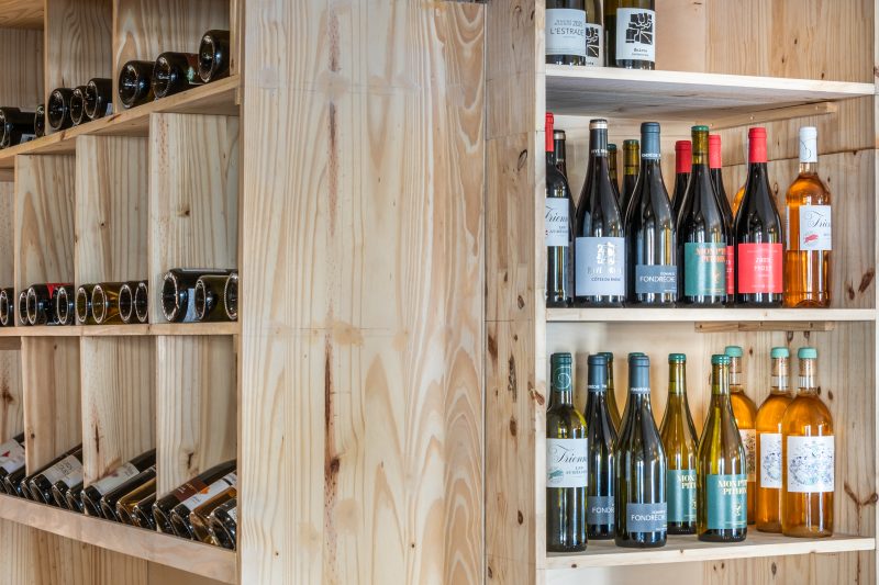 La cave à vins : bouteilles rangées dans des casiers en bois clair.