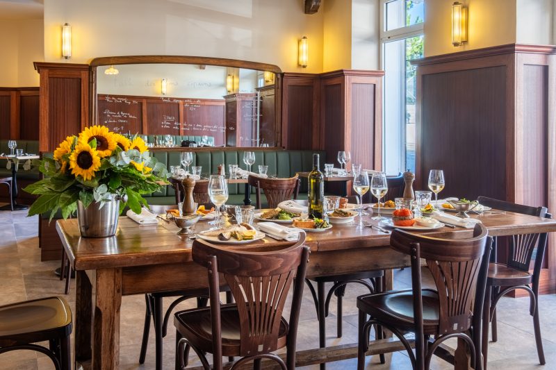 La salle et son grand miroir de bistrot, tables dressées pour le déjeuner.