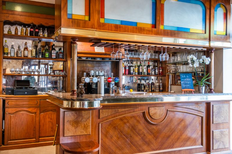 Le bar en bois, ses vitraux et ses bouteilles.