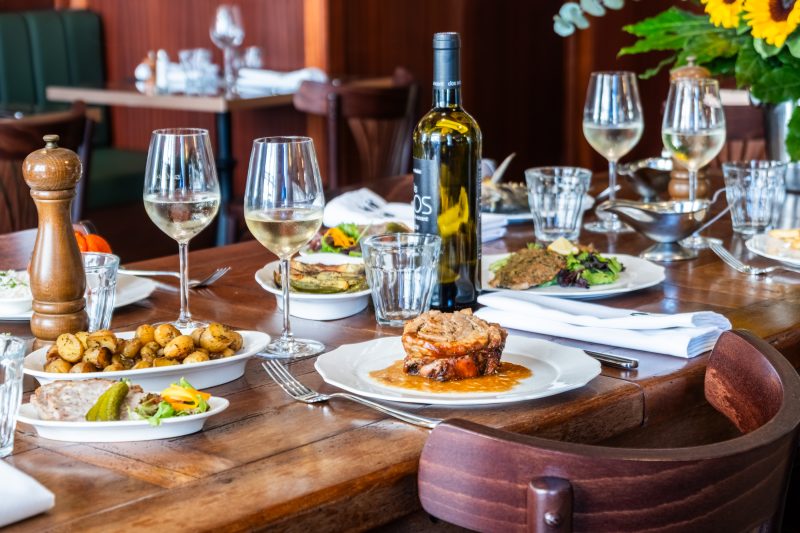 Une table servie, verres de vin blanc et bouteille, au milieu de la salle.